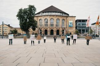 Aktivist:innen mit Demoschildern zum Earth Overshoot Day vor dem Stadttheate