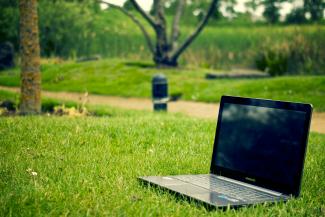 Ein Laptop steht im Gras.