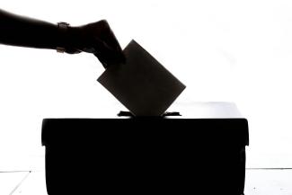 Hand wirft einen Umschlag in eine Box